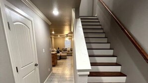 A staircase with wooden steps and white railings, leading to a living area with a sofa and a coffee table. - New Luxury 3 Bed 2 1/2 Bath Duplex (Barling)