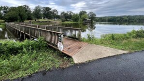 A wooden bridge over a calm lake with a sign prohibiting dogs. - New Luxury 3 Bed 2 1/2 Bath Duplex (Barling)