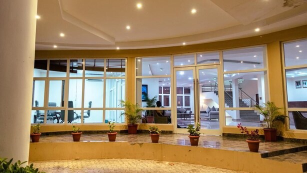 A spacious lobby with large windows, potted plants, and a visible staircase leading to upper floors. - Golden Alpine Hotel & Resort (Jimeta)