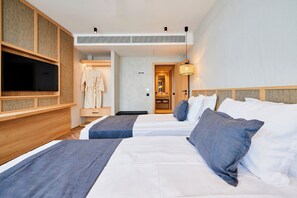 A hotel room with two beds, a TV, a robe, and a bathroom visible through an open door.