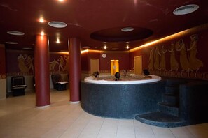 A spa area with a circular hot tub, red pillars, and wall murals.