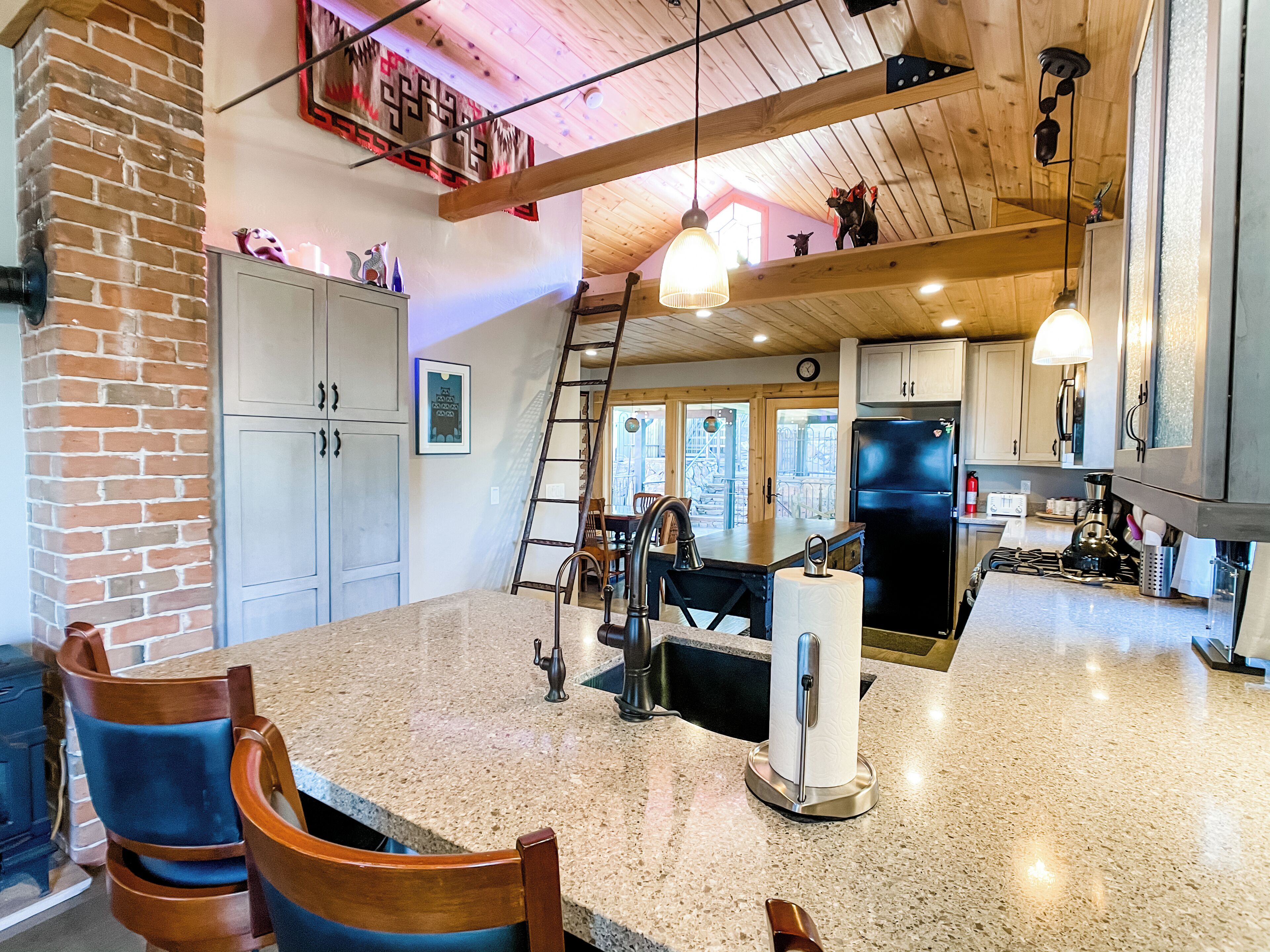 A spacious kitchen with granite countertops, a central island, and a dining area with wooden chairs.