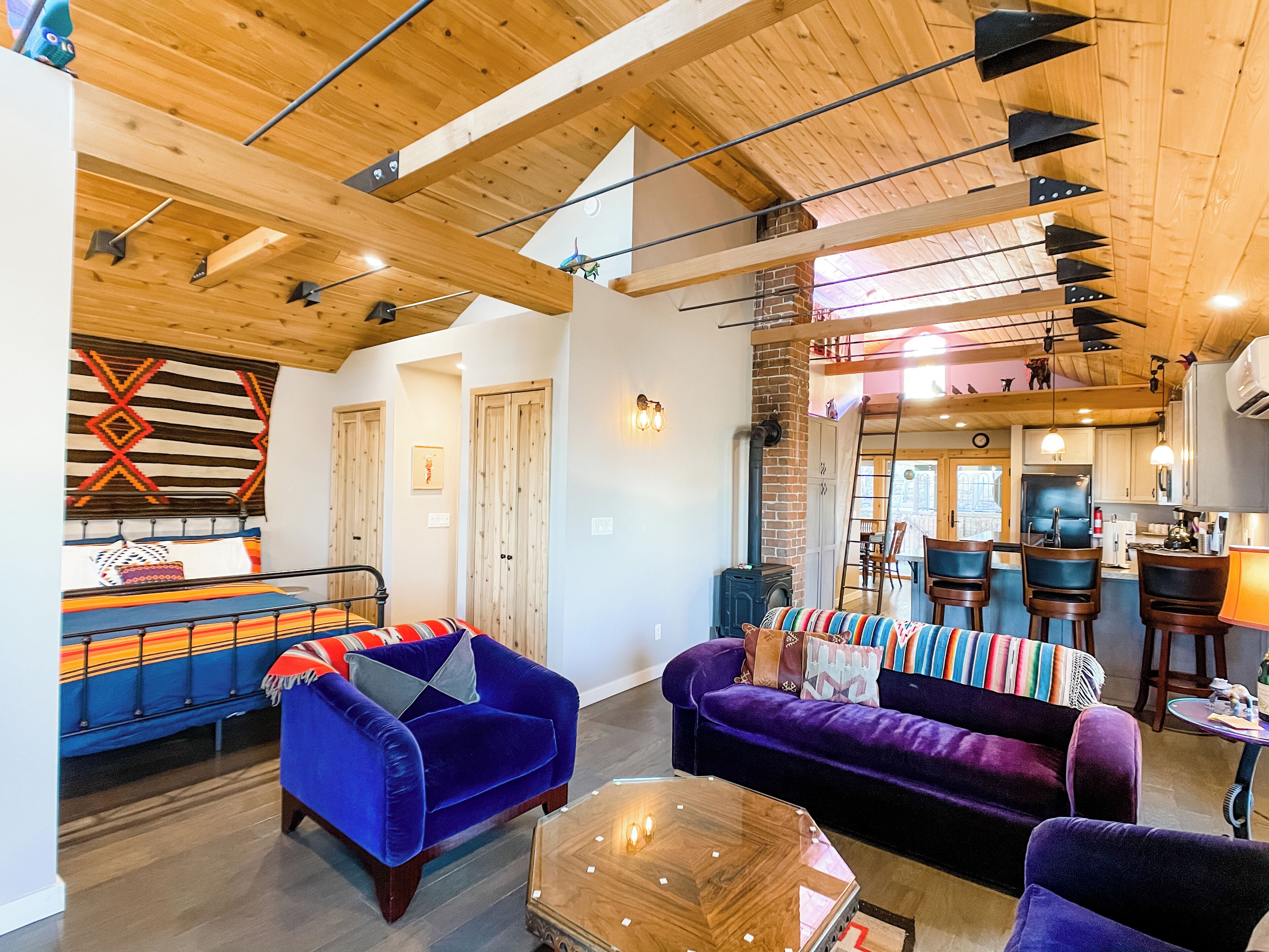Een gezellige woonkamer met houten plafond, een open haard en een eethoek met tafel en stoelen.