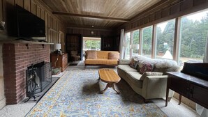 Un salon chaleureux avec une cheminée, un canapé, une table basse et un téléviseur.