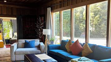A cozy living room with a large window, a sofa, a coffee table, and a patterned rug.