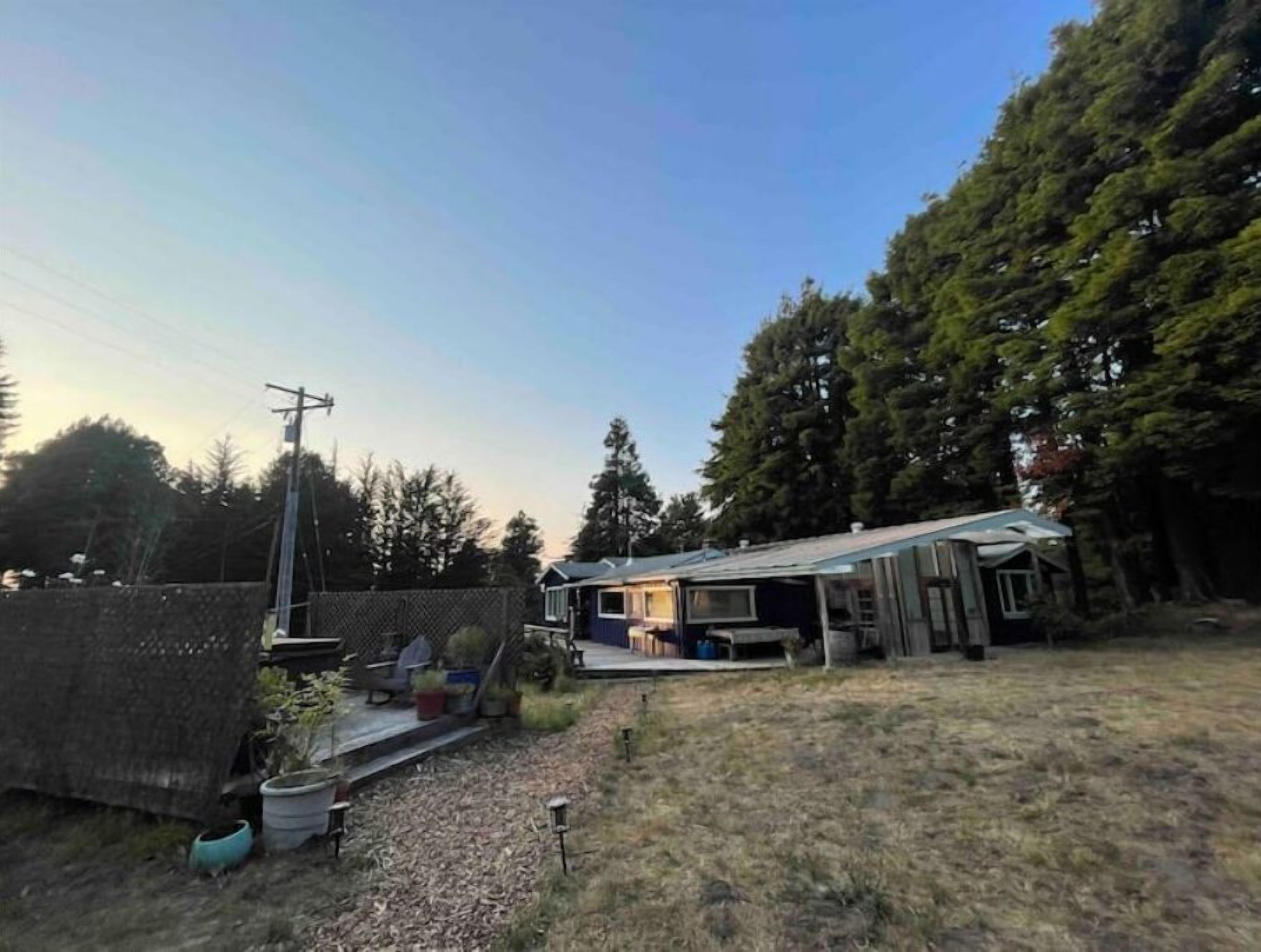 Un jardin à l’arrière d’une maison, avec une clôture et un chemin de gravier.
