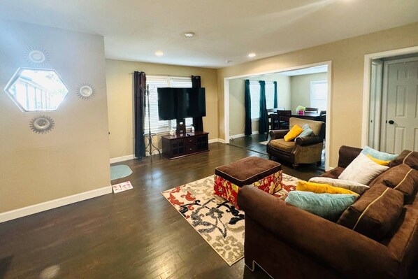 A living room with a brown sofa, a coffee table, and a flat-screen TV on a stand.