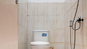 A small, tiled bathroom with a toilet, a shower, and a patterned floor.