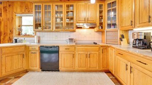 A kitchen with wooden cabinets, a dishwasher, and a microwave. - 1902 Family Lakehouse: Screened Porch & Views (Queensbury)