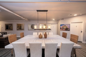 Un espace repas moderne avec une longue table, des chaises blanches et des vases décoratifs.
