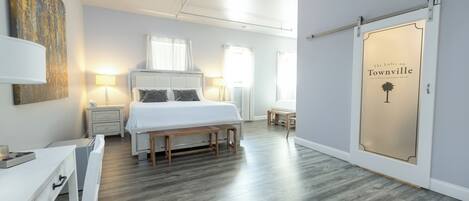 A modern bedroom with a large bed, bedside tables, a desk, and a sliding door with a sign.