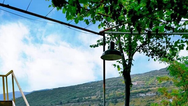 A wooden table with a view of a mountainous landscape, surrounded by wooden stumps and a ladder. - Veranda Vere (Tbilisi)