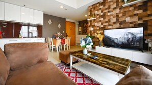 A modern living room with a large flat-screen TV, a brown sofa, a wooden coffee table, and a patterned rug. - Wonderful 2 bedrooms condo in T1 Masteri Thao Dien (Ho Chi Minh City)