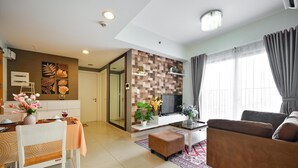 A modern living room with a sofa, a dining table with chairs, a TV, and a decorative wall. - Wonderful 2 bedrooms condo in T1 Masteri Thao Dien (Ho Chi Minh City)