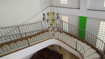 A multi-level interior with a curved staircase, metal railings, and a hanging light fixture.