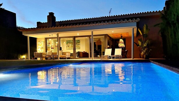 A swimming pool with a tiled deck, a covered patio area with seating, and a large window overlooking the pool. - Villa Torrent , con Piscina Privada (Torrent)