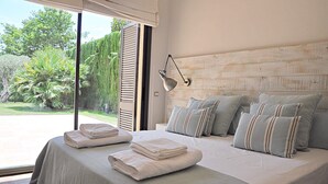 A bedroom with a large bed, a view of the garden, and a wooden headboard. - Villa Torrent , con Piscina Privada (Torrent)