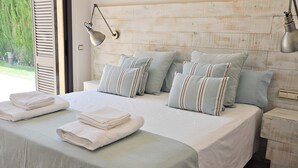 A neatly made bed with pillows and folded towels, a bedside table, and a lamp. - Villa Torrent , con Piscina Privada (Torrent)
