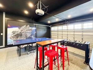 Enjoy games and entertainment in this room featuring a ping pong table, foosball table, and large screen.