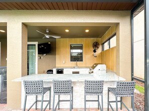 Enjoy dining and cooking in this spacious kitchen area with a large island countertop, sink, and wall-mounted TV.