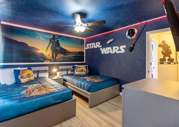A Star Wars-themed bedroom with two beds, a ceiling fan, and a mural of a desert planet.