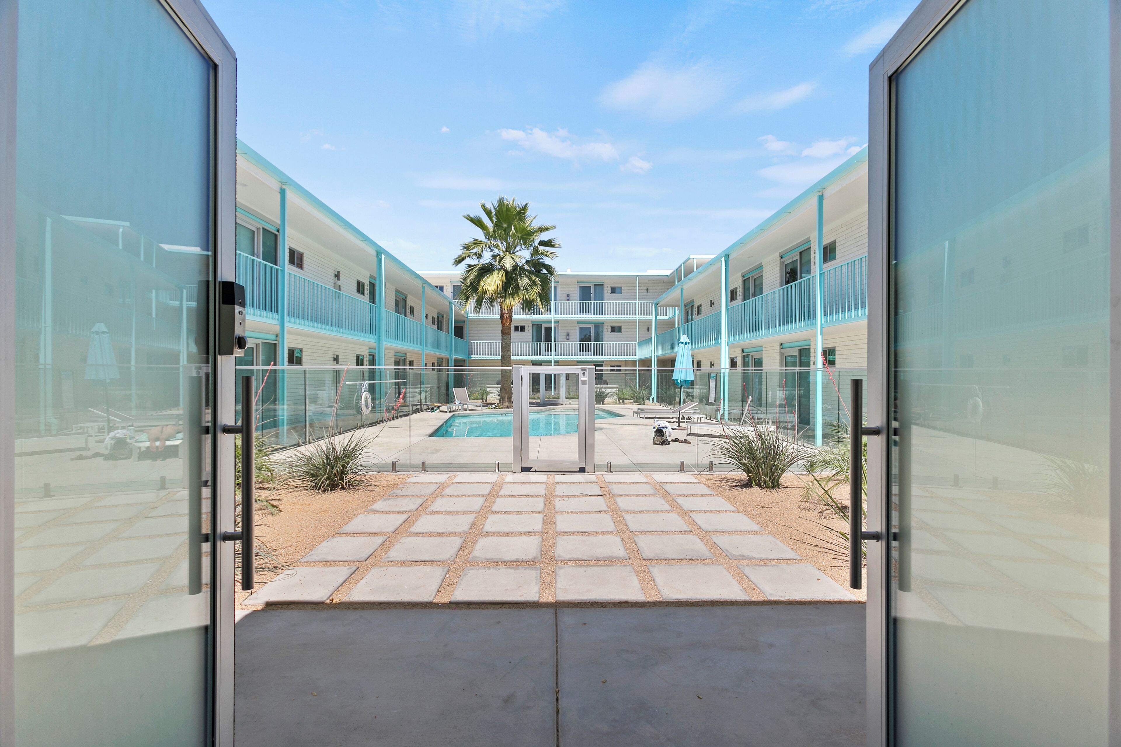 Un edificio moderno con un patio central, una piscina y una palmera.