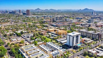 Vista aérea de un paisaje urbano con una mezcla de edificios residenciales y comerciales, incluyendo un hotel destacado con piscina en la azotea.