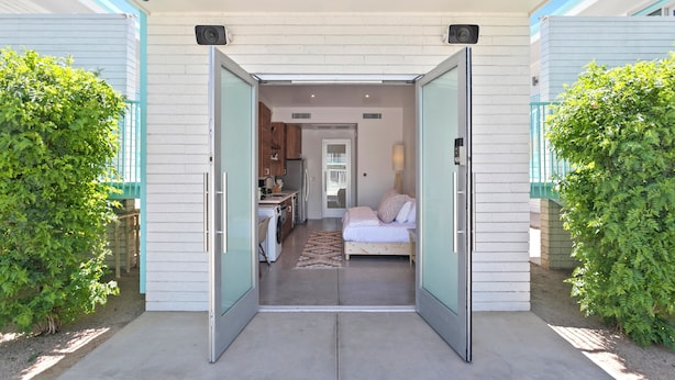 A modern, open-plan living space with a kitchen, dining area, and a bedroom with a bed and nightstand. - Funky Pool Side Cabana in DTPHX (Phoenix)