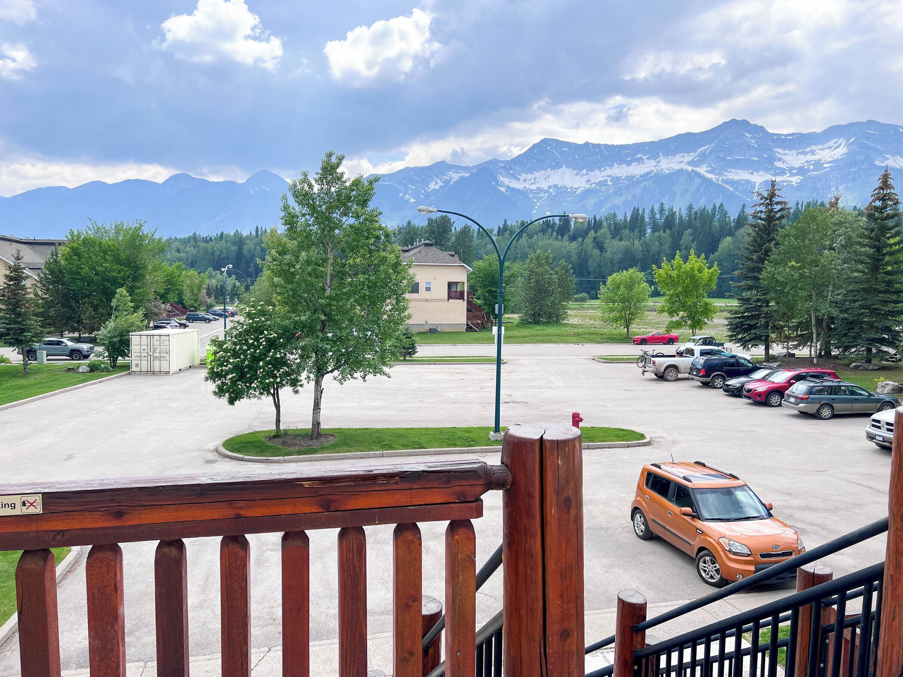 A parking area with cars, a building, and a mountain range in the background.