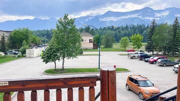A parking area with cars, a building, and a mountain range in the background.