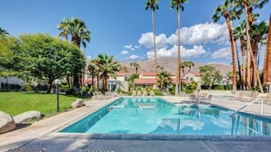 Una piscina con lettini, palme e una montagna sullo sfondo.