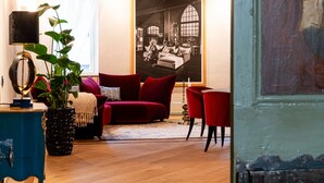 A living room with a red sofa, a blue side table, and a large painting on the wall.