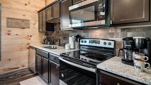Una cucina moderna con elettrodomestici in acciaio inossidabile, un piano di lavoro in granito e pareti rivestite in legno.