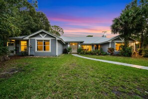 A two-story house with a well-maintained lawn, a driveway, and a large tree in the front yard. - The Rustic Resort - 2 Homes, Pool, Building, Golf! Sleeping for up to 30! (Jupiter)