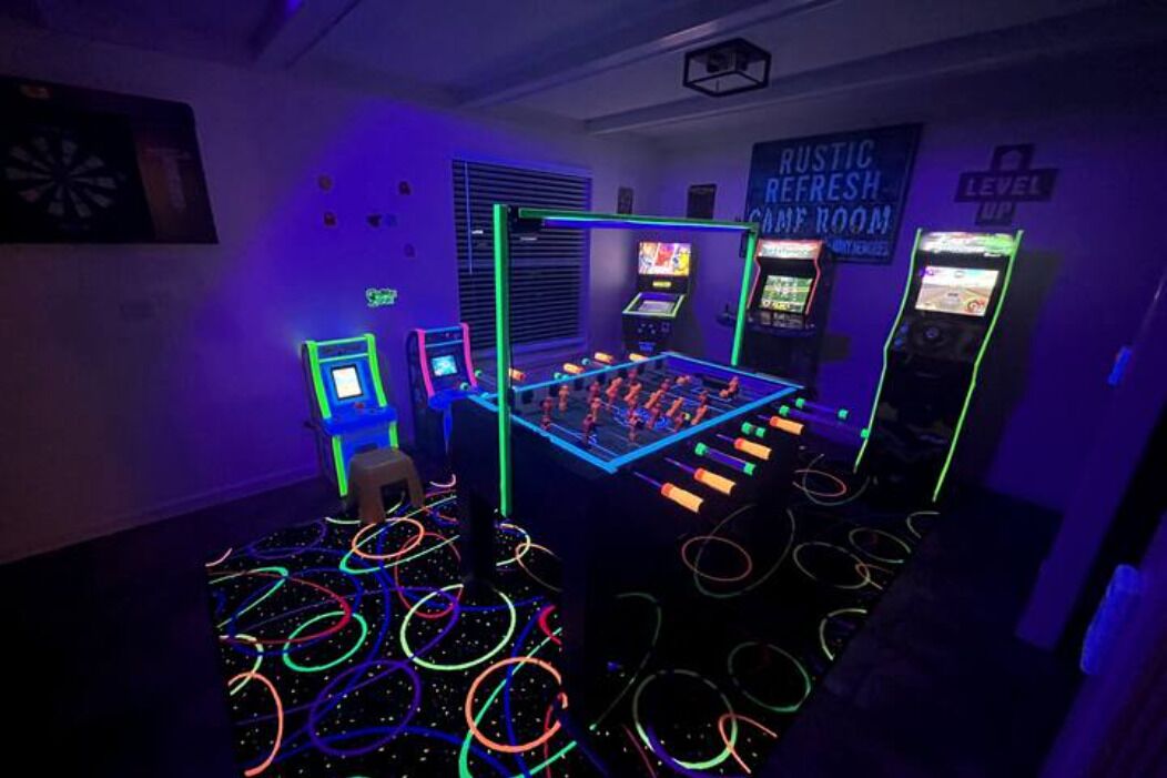 Une pièce éclairée de néons, avec un baby-foot et des jeux d’arcade.