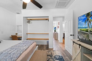 A bedroom with a bed, a desk, a ceiling fan, a TV, and a view of the outdoors. - The Rustic Resort - 2 Homes, Pool, Building, Golf! Sleeping for up to 30! (Jupiter)