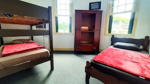 A room with two bunk beds, a wooden wardrobe, and a television on top. -  Sétimo Hostel 7 (São Paulo)