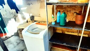 A room with a washing machine, a sink, and shelves with cleaning supplies. -  Sétimo Hostel 7 (São Paulo)