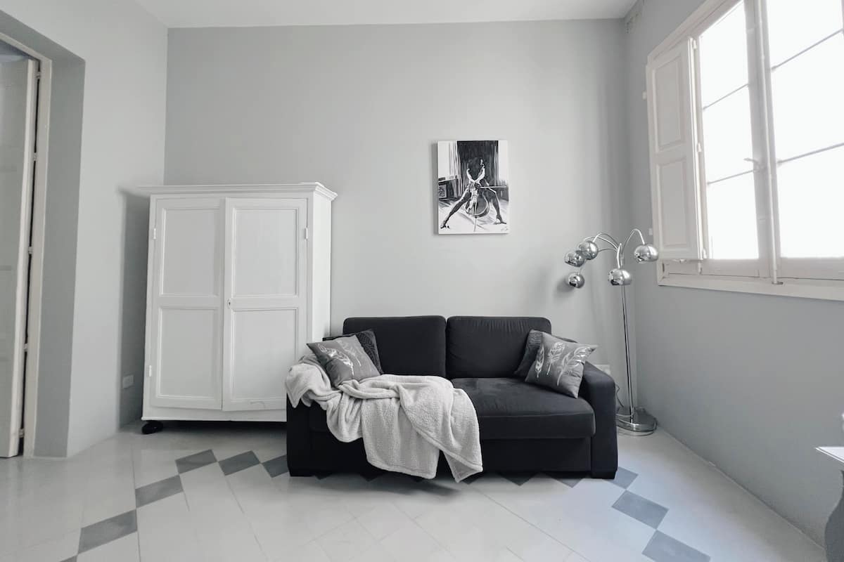 Un salon moderne avec un canapé noir, un meuble blanc et un lampadaire.