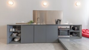 A modern kitchen with grey cabinetry, a built-in oven, and a stainless steel sink.