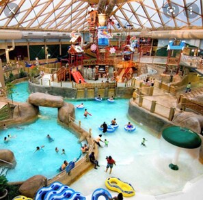 An indoor water park with multiple pools, slides, and water play areas.