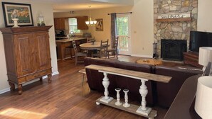 A spacious living room with a stone fireplace, a wooden dining table, and a kitchen in the background. - Cozy Fall retreat in Massanutten Four Season Mountain Resort ski, bike, fish (McGaheysville)