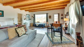 A cozy living room with a wooden ceiling, a sofa, a dining table, and a view of the outside. - Pet-Friendly El Prado Vacation Rental w/ Views! (El Prado)