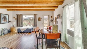 A cozy room with a wooden ceiling, a bed, a dining table with chairs, and a window with curtains. - Pet-Friendly El Prado Vacation Rental w/ Views! (El Prado)
