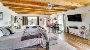 A spacious bedroom with a large bed, a ceiling fan, wooden beams, a TV, and a view of the outdoors. - Pet-Friendly El Prado Vacation Rental w/ Views! (El Prado)