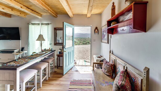 A cozy room with a wooden ceiling, a large window, a TV, a desk with a lamp, and a bench. - Pet-Friendly El Prado Vacation Rental w/ Views! (El Prado)