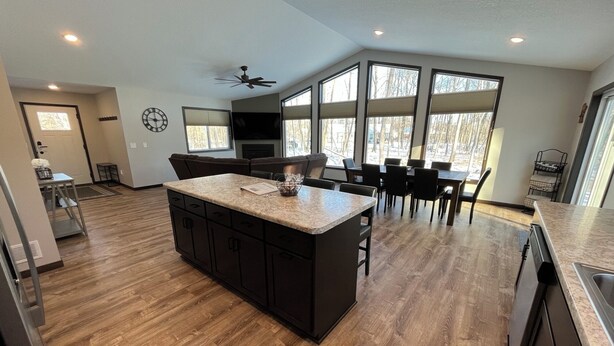 A modern kitchen with a central island, dark cabinetry, and large windows providing natural light. - The Ridge - NEW Modern Home! (Onamia)
