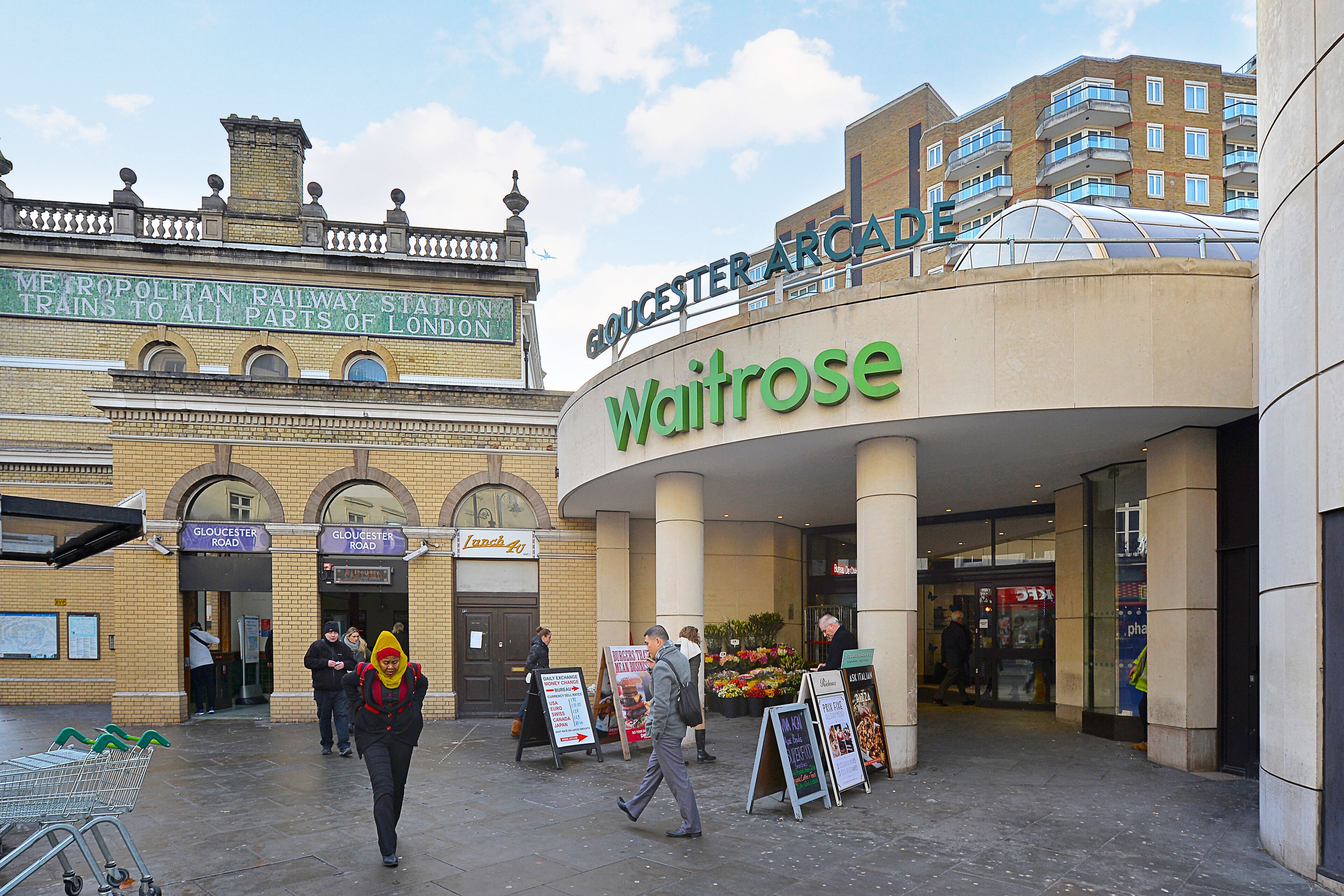 A Waitrose store with a sign above the entrance and a sign for Gloucester Road.