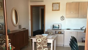 A compact kitchen with a microwave, toaster, and sink. There is a dining table with chairs and a cabinet with a mirror. - TORREGRANDE BEACH ORISTANO (Torre Grande)