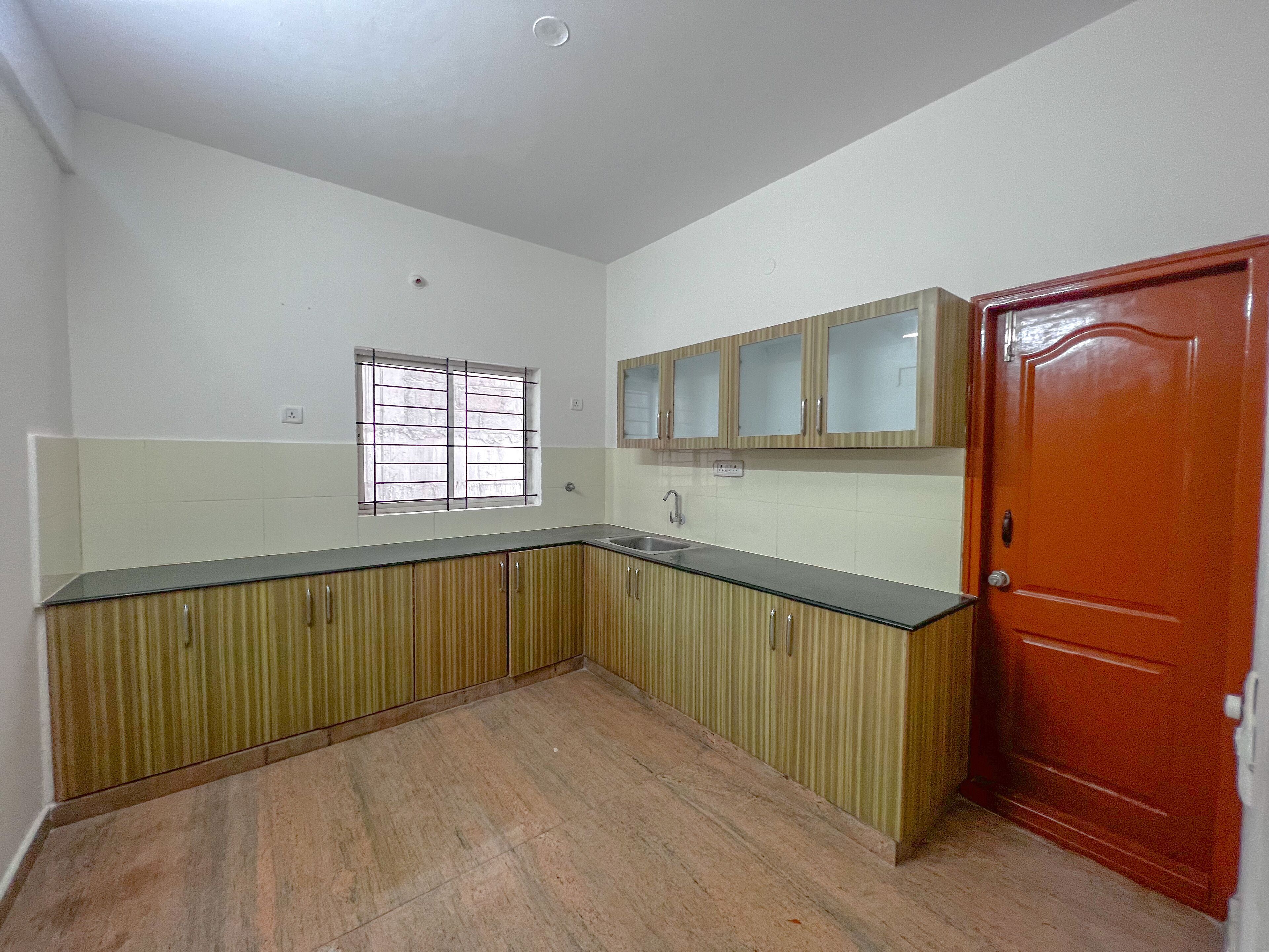 A kitchen with wooden cabinets, a sink, and a window with bars.